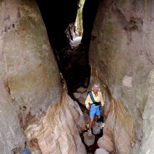 A tour guest explores the narrow crevice leaving to an enclosed amphitheatre on our Uniquely Australia, Land of Contrasts Tour