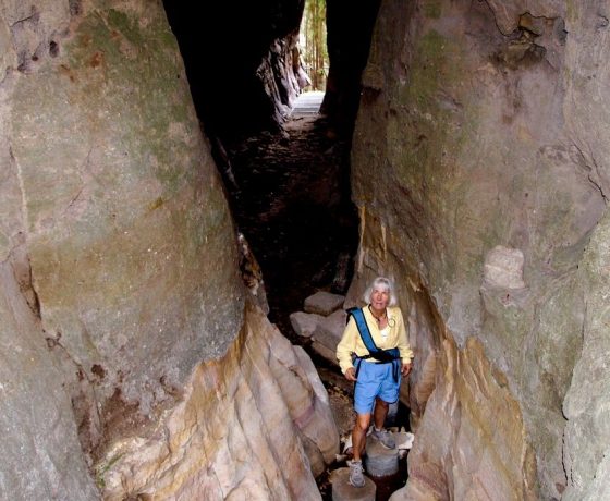 A tour guest enters the unique geological feature of a sunken amphitheatre through this crevice. Inside is a place of peace and wonder