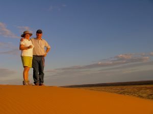 Tour guests greet the sunset on top of 'Big Red' in Corner Country Outback Tour