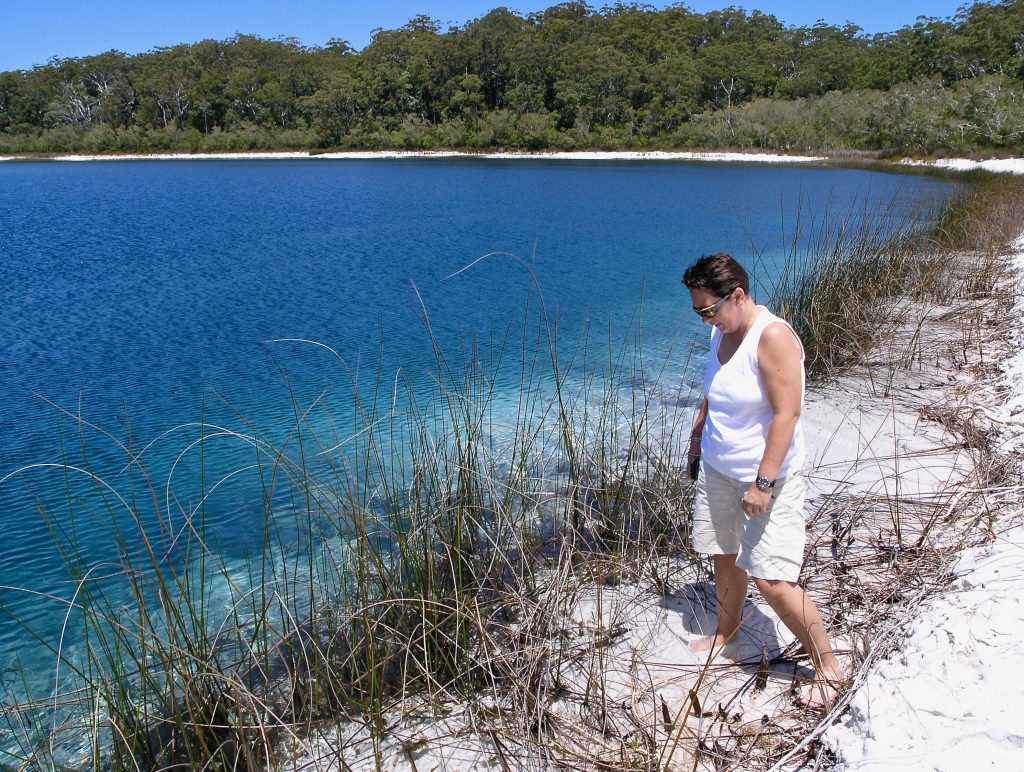 Tour guest enjoys health and wellbeing examining a lakeside ecosystem of Lake McKenzie Fraser Island